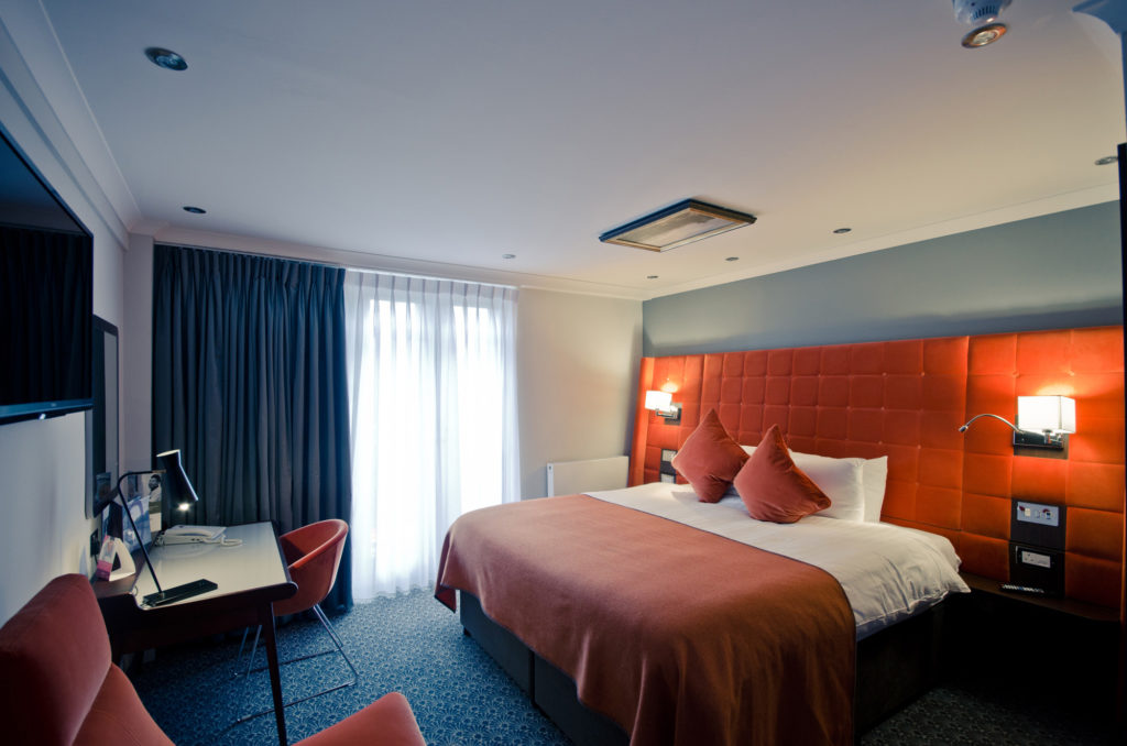 Privilege room, big comfy bed with orange headboard and bedspread