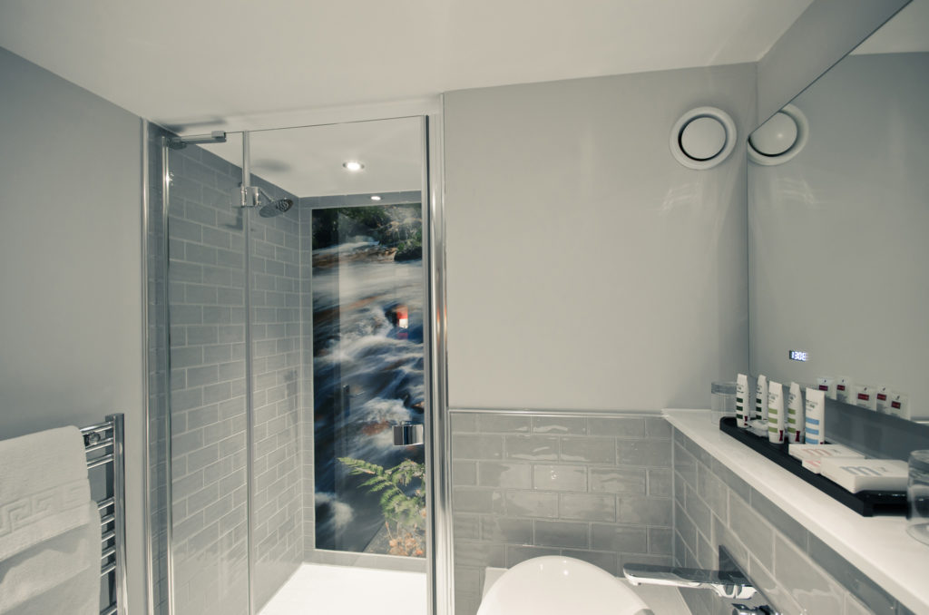 Privilege room shower in bathroom with photographic mural of nature scene on wall, grey tiles