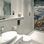 Superior room wet room shower with photographic mural on wall of nature scene with grey tiles, white sink and toilet